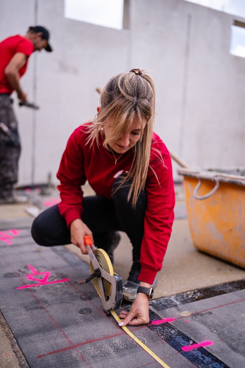 Frau im roten Haberl-Pulli misst auf der Baustelle aus